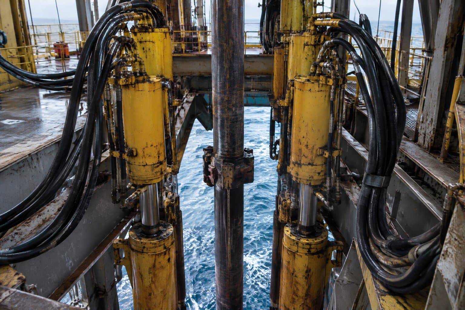 Riser tensioner cylinders with looping hydraulic hoses around a floating rig's moonpool