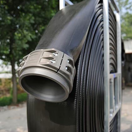 Grooved-end aluminium coupling clamped on black lay flat hose wound on a reel