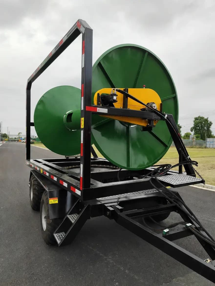 Green 3-point hitch lay flat hose reel with yellow hydraulic motor cover on a stand