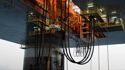 Tensioner and compensator hose assemblies hanging under a drilling rig
