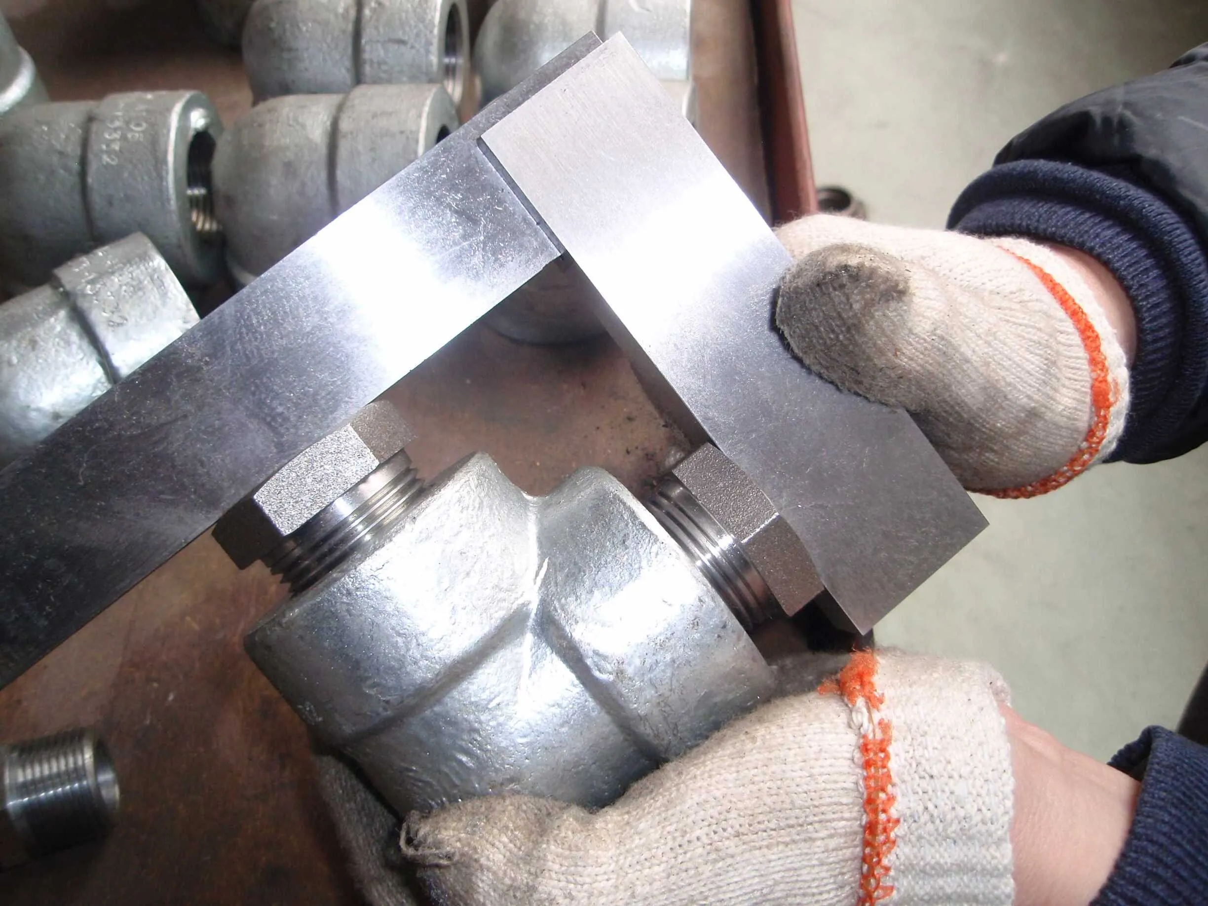 Two precision squares checking the socket ends of a forged fitting for square