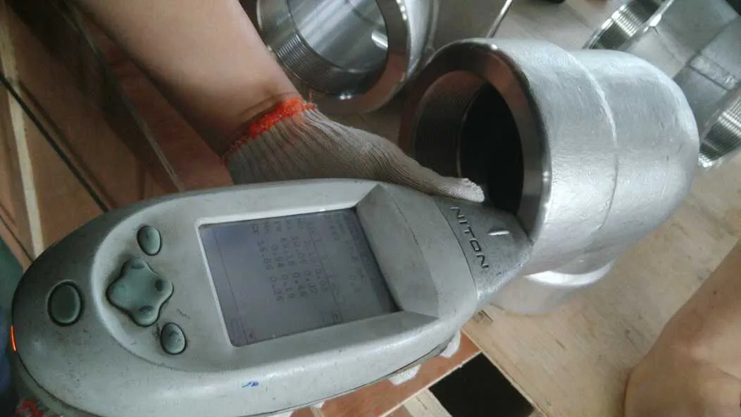 Handheld XRF analyser reading alloy composition on a threaded fitting